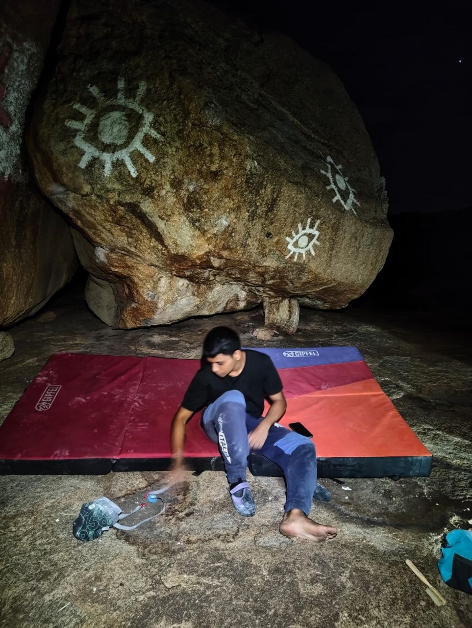 Me sitting under stars in front of a boulder getting ready to climb it